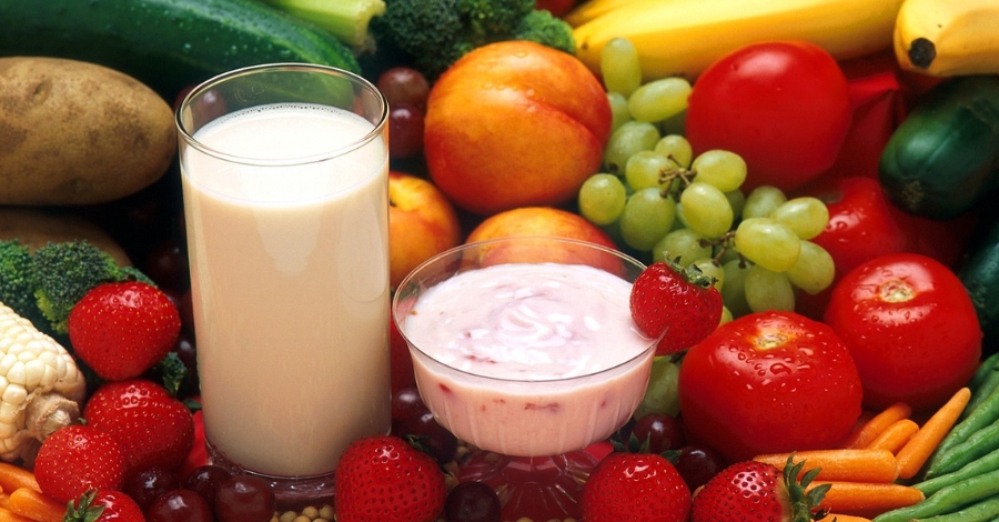 Imagem com alimentos saudáveis - frutas, verduras, legumes, leite e iogurte sobre a mesa.